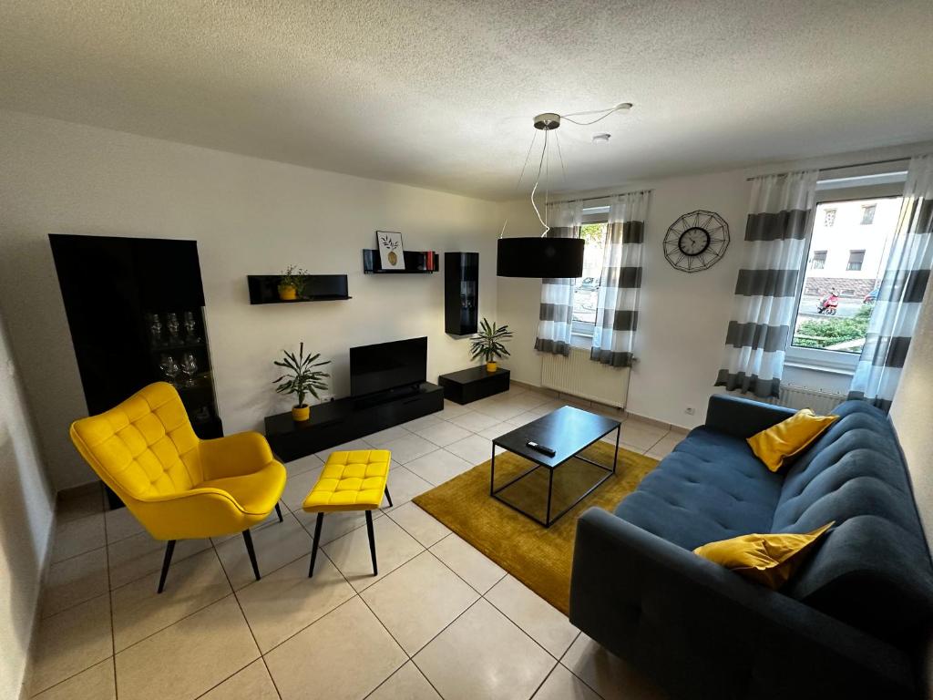 a living room with a blue couch and yellow chairs at Giulia Ferienwohnung - Zentral in Tuttlingen