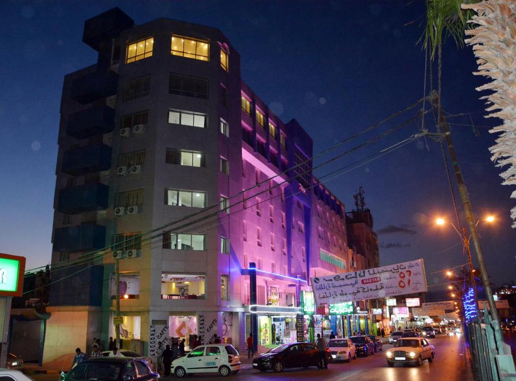 a building with purple lighting on a city street at night at Seven Days Hotel in Irbid
