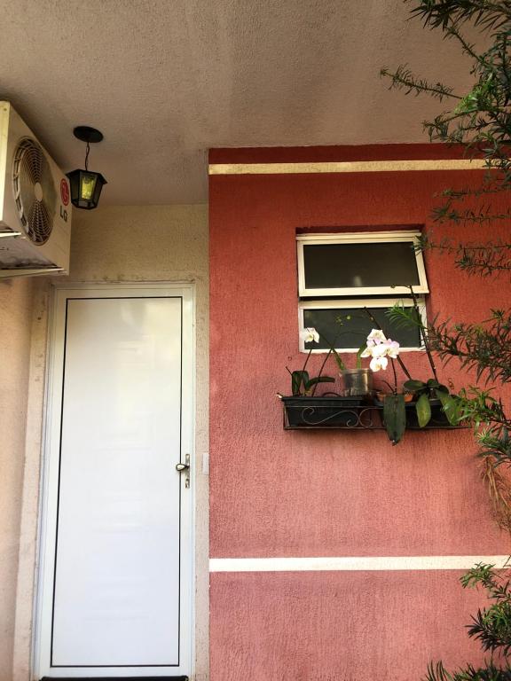 une porte menant à une maison avec une fenêtre et des fleurs. dans l'établissement Residencial Parque da Liberdade IV, à Sao Jose do Rio Preto
