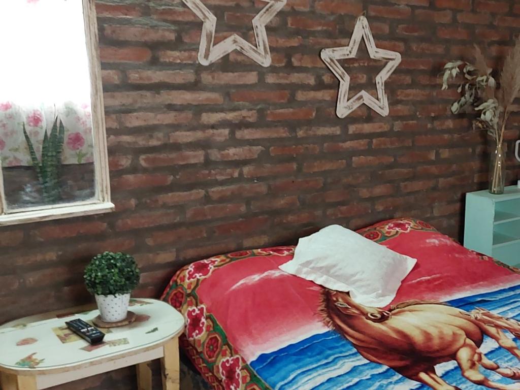 1 dormitorio con cama con almohada de gallo y mesa en Finca los Arcos en Santiago del Estero