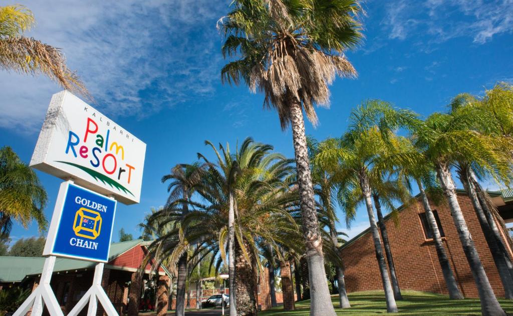 a palm roof sign and palm trees in front of a building at Kalbarri Palm Resort in Kalbarri