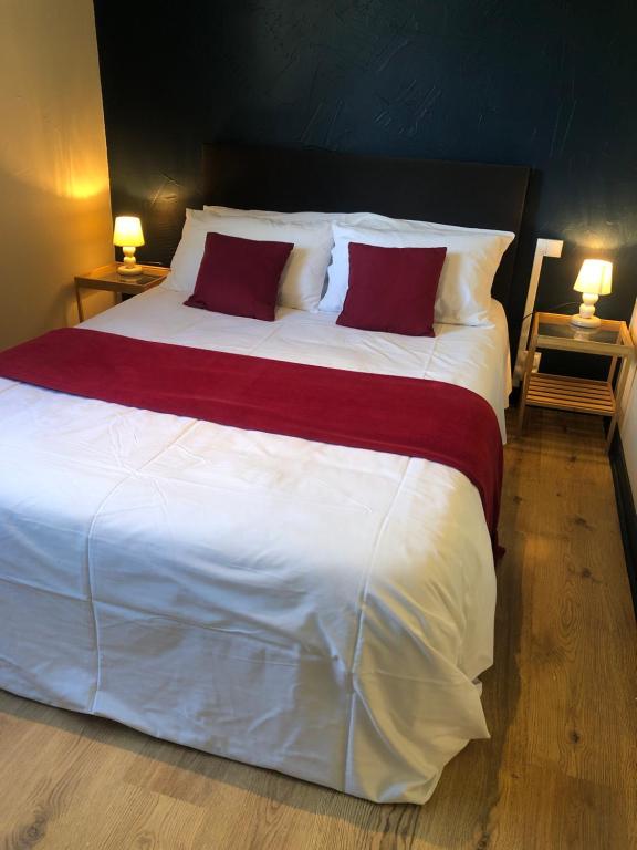 a large white bed with two red pillows on it at CONTACT HOTEL LE BOIS SAUVAGE in Saint-Agrève