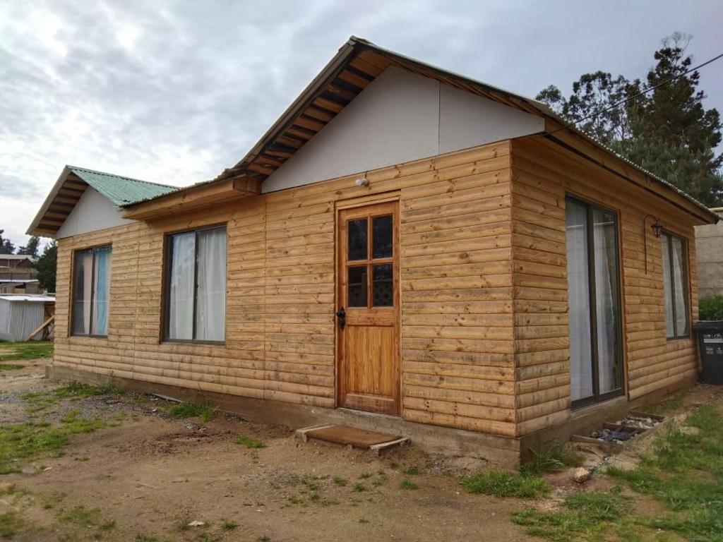una pequeña casa de madera con puerta de madera en S&J Casa Cabaña, en El Tabo