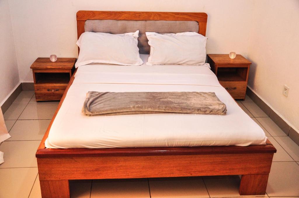 a bed with a wooden frame and two night stands at LES LOGIS DE NOUVELLE ROUTE BASTOS in Yaoundé