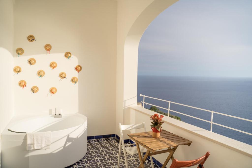 a bathroom with a tub and a balcony with the ocean at Pezz Pezz in Praiano