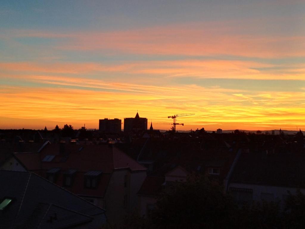 een uitzicht op de zonsondergang van een stad met daken bij Wohnung Waldstadt-Zentrum in Karlsruhe