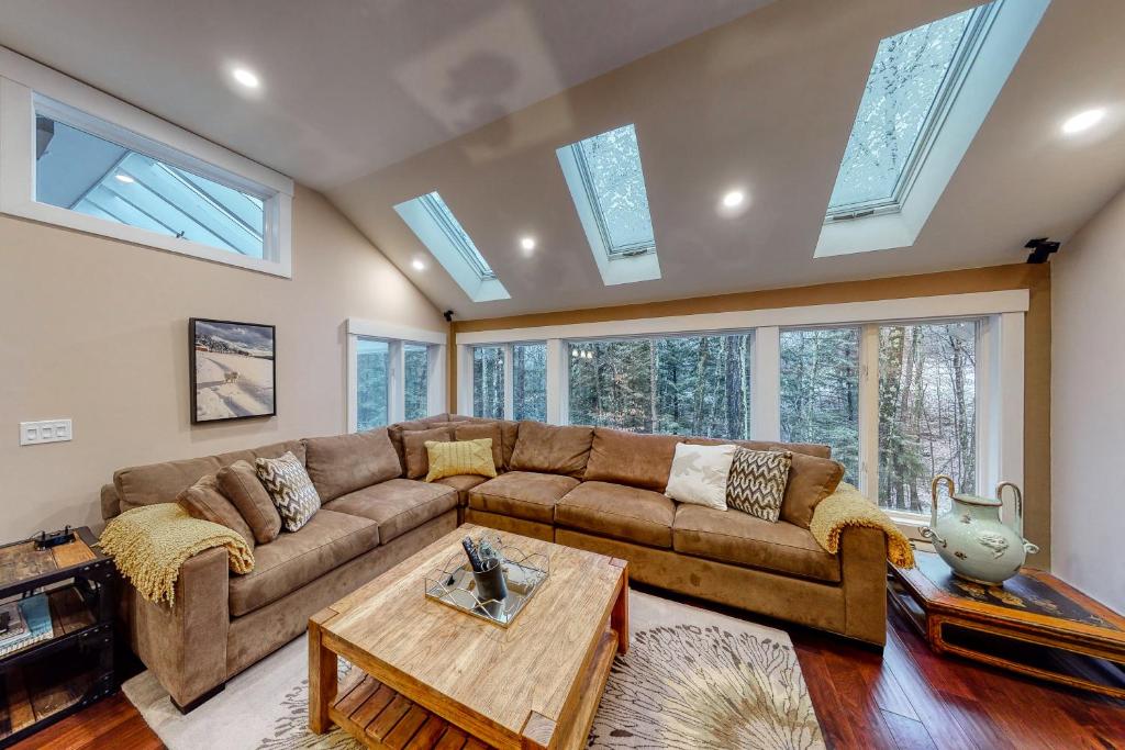 ein Wohnzimmer mit einem braunen Sofa und einigen Fenstern in der Unterkunft Club Sugarbush 31 32 in Warren