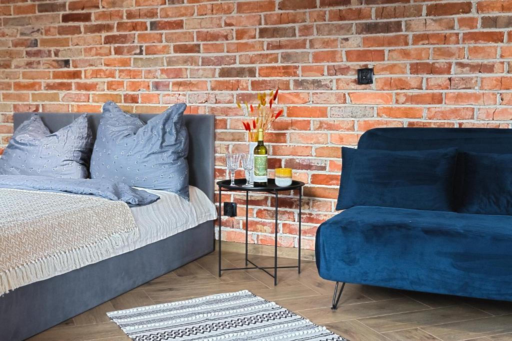 a bedroom with a blue bed and a brick wall at Loft deLUX in Bielsko-Biała