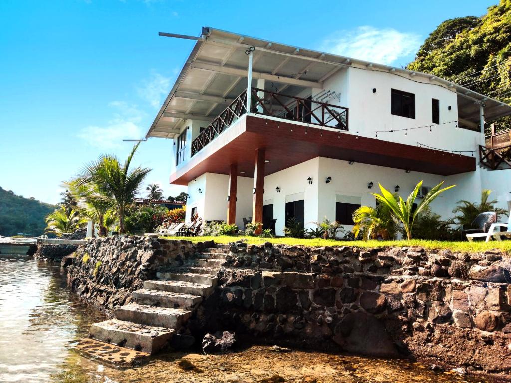 a house on a rock wall next to the water at Kasakai Beachouse in Juan Gallego
