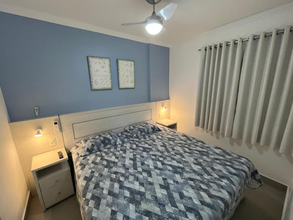 1 dormitorio con cama y pared azul en FLAT RIVIERA COM VISTA MAR A 150m DA PRAIA ! MÊS DE MAIO MENOR TARIFA DO ANO - APROVEITE !, en Riviera de São Lourenço