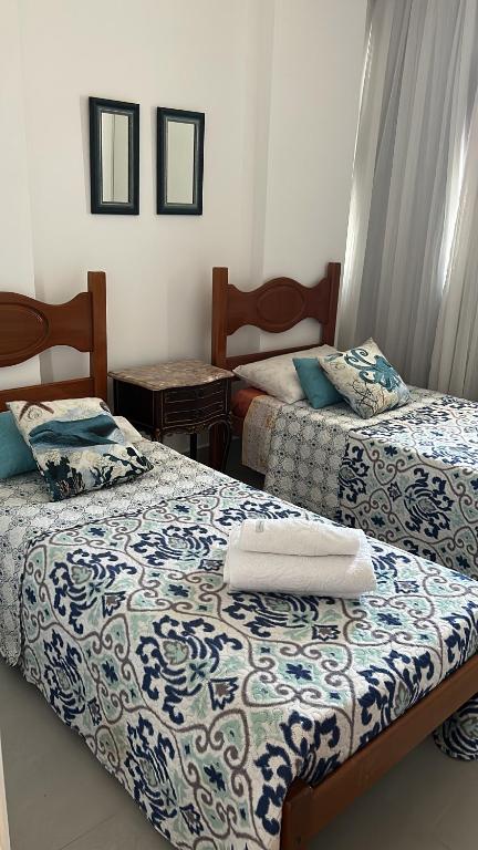 a bedroom with two beds with blue and white sheets at Apartamento vista do mar, pé na areia e águas tranquilas, no cento de Guarapari in Guarapari