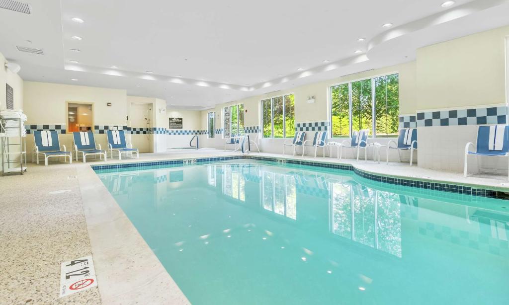 Hampton Inn Nashua في ناشوا: حمام سباحة في غرفة الفندق مع كراسي زرقاء