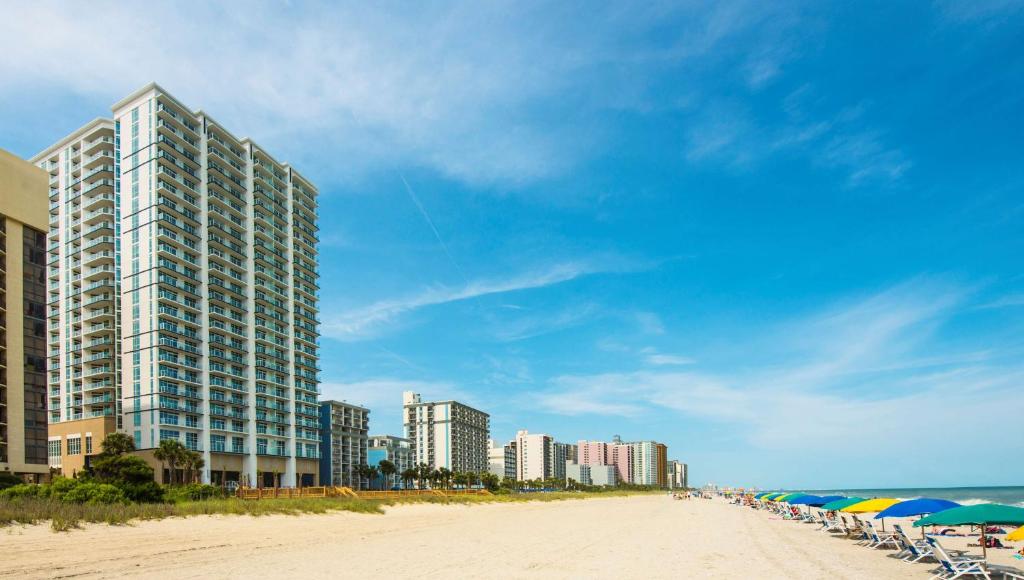 einen Strand mit Stühlen, Sonnenschirmen und Gebäuden in der Unterkunft Hilton Grand Vacations Club Ocean 22 Myrtle Beach in Myrtle Beach