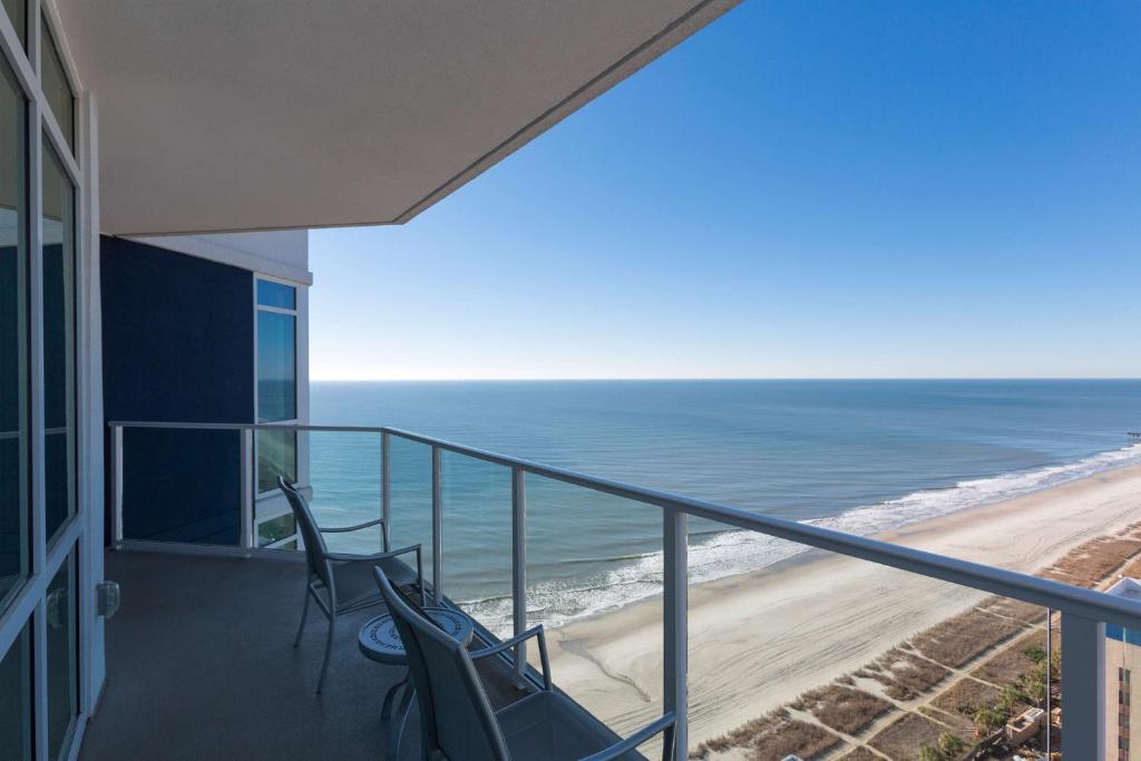 a balcony with chairs and a view of the beach at Hilton Grand Vacations Club Ocean 22 Myrtle Beach in Myrtle Beach