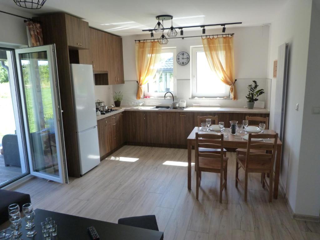 kuchnia ze stołem i krzesłami oraz kuchnia z lodówką w obiekcie Sosnówka - domki nad morzem w mieście Kopalino