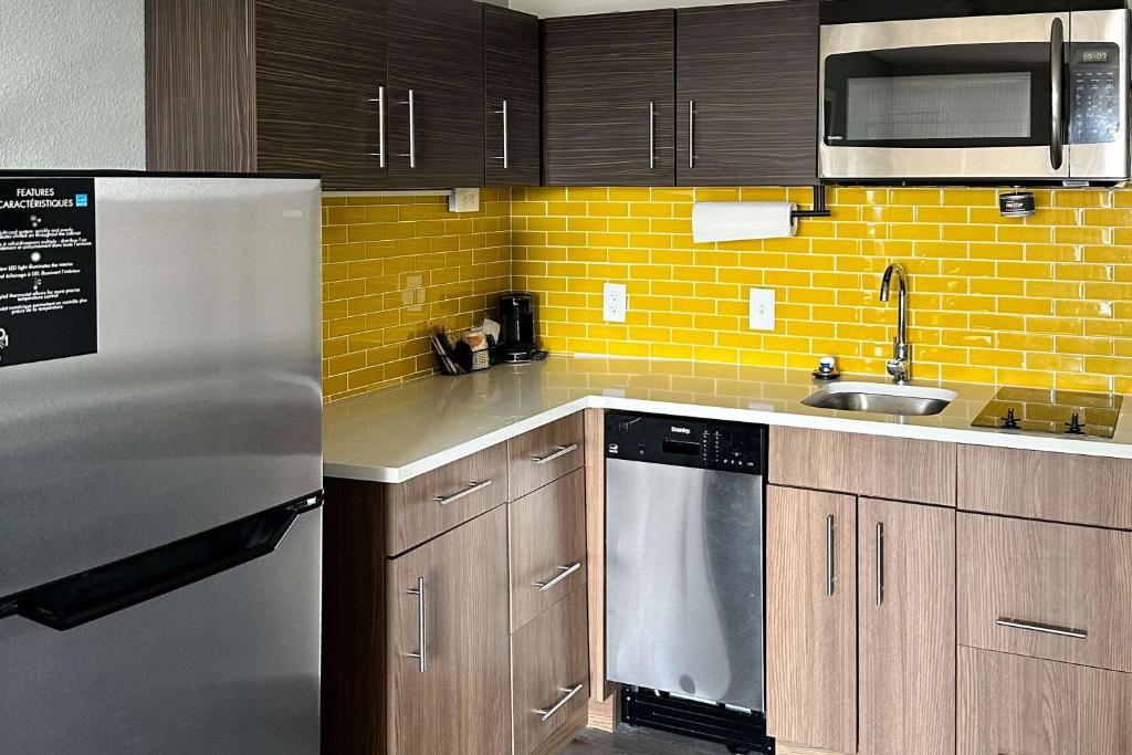 eine Küche mit Holzschränken und einem Kühlschrank aus Edelstahl in der Unterkunft MainStay Suites in Conover