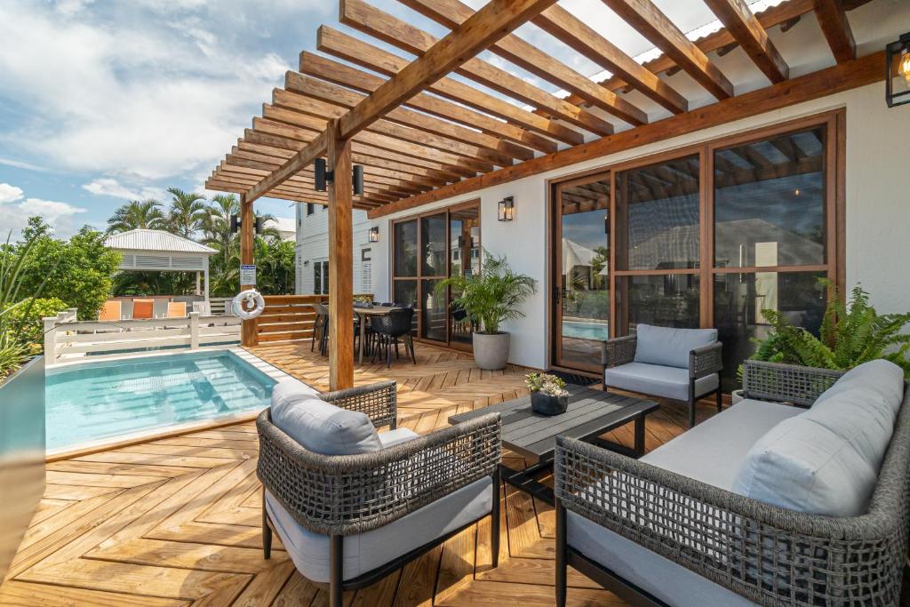 an outdoor patio with a pool and a wooden deck at Conch Shell Cottage and The PoolClub at Mahogany Bay! in San Pedro
