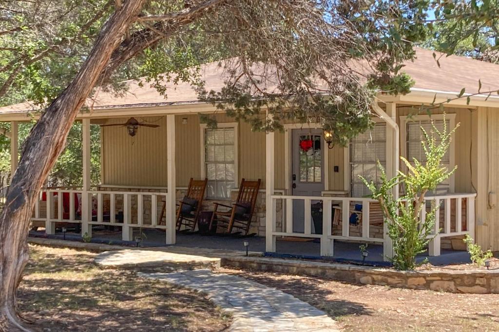 una casa con un porche con sillas. en Meadow Creek Cottage en Wimberley