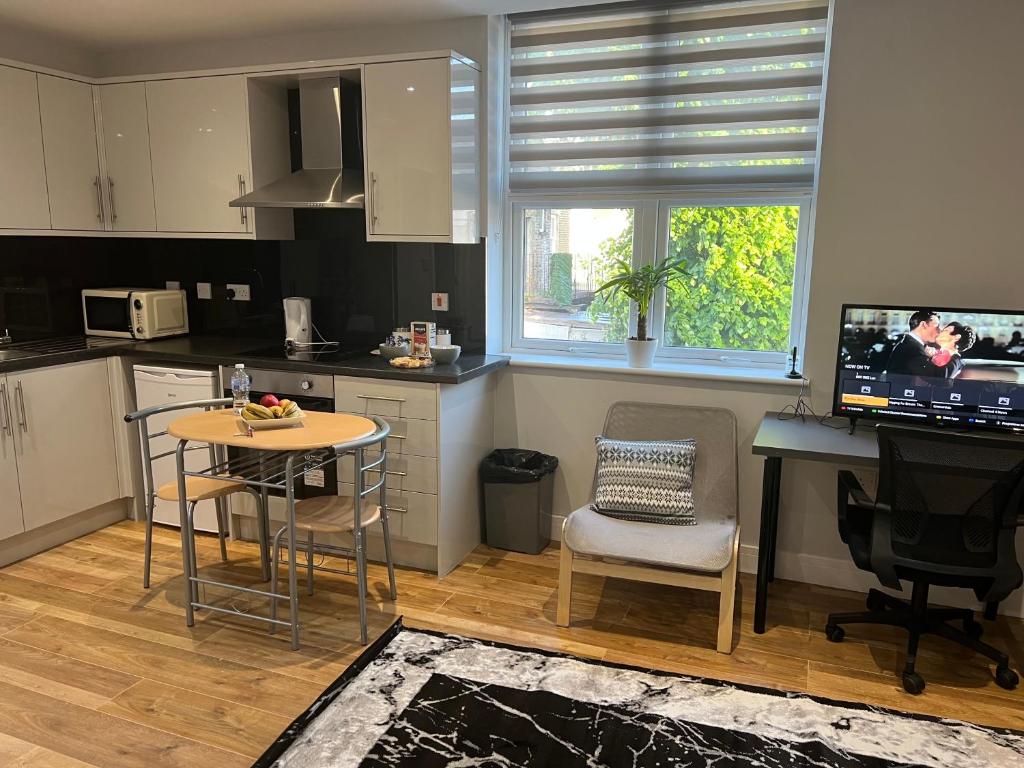 a kitchen with a table and a desk with a television at MJ Serviced Apartment up to 6 Guest - Luxurious living in West London next to Tube station & Central London in Hanwell