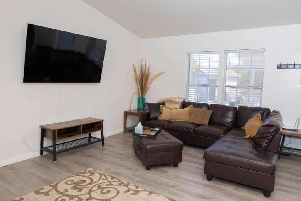 a living room with a leather couch and a flat screen tv at HERITAGE HOUSE GREAT FOR GROUPS!!! in Pahrump
