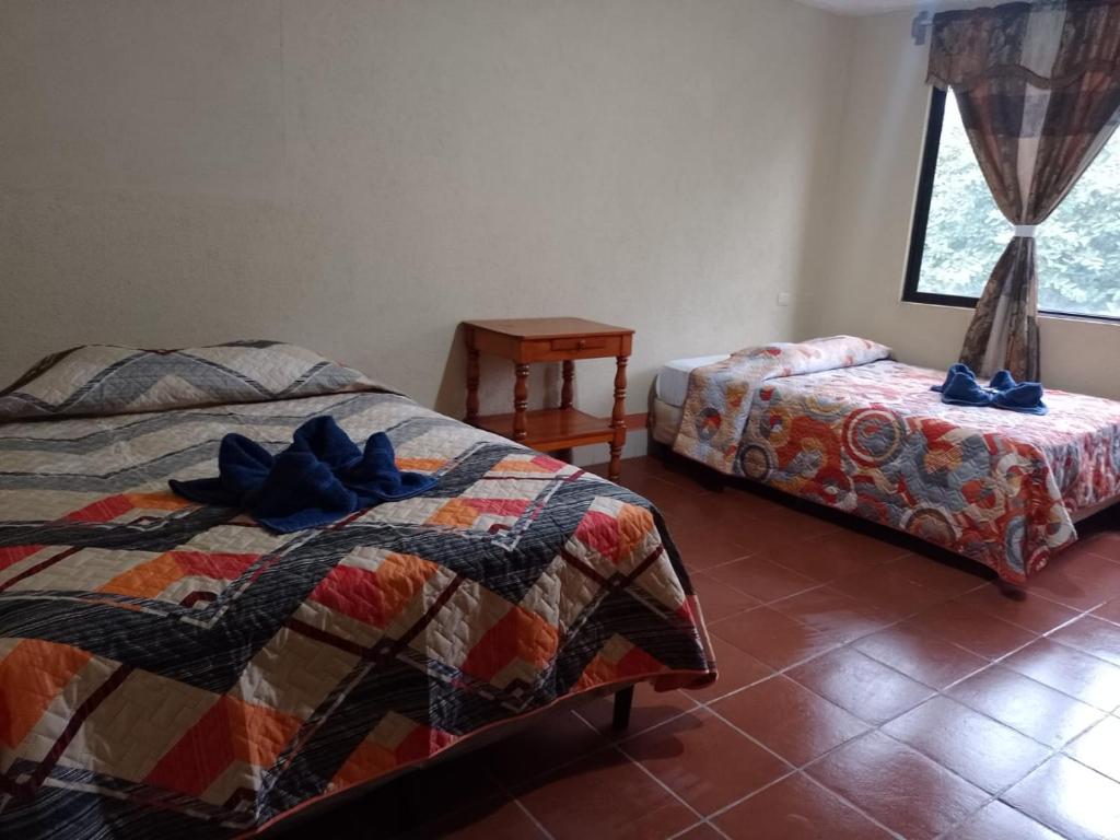 a bedroom with two beds and a table and a window at Hostal Sweet Dreams in Panajachel
