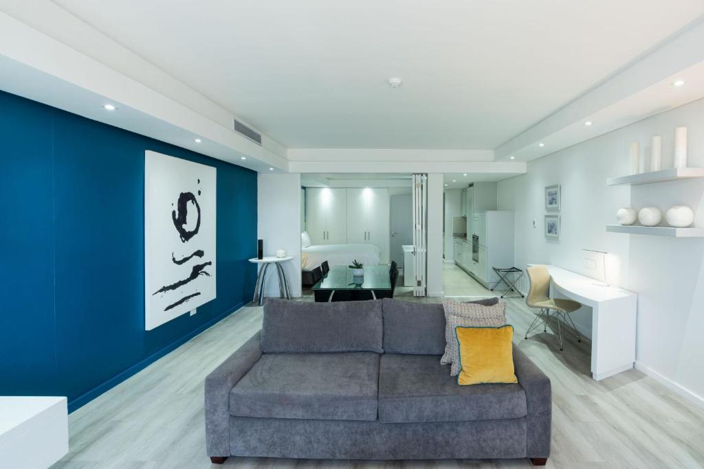 a living room with a gray couch and a blue wall at Protea Hotel by Marriott Cape Town North Wharf in Cape Town