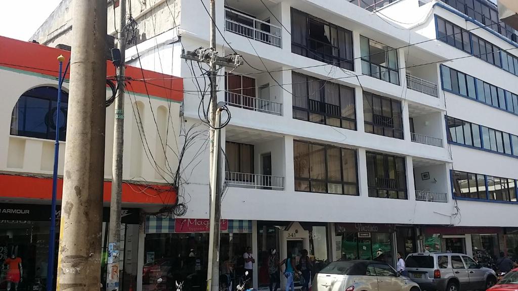 Un edificio alto y blanco con coches aparcados delante. en Apartamentos Salome, en San Andrés