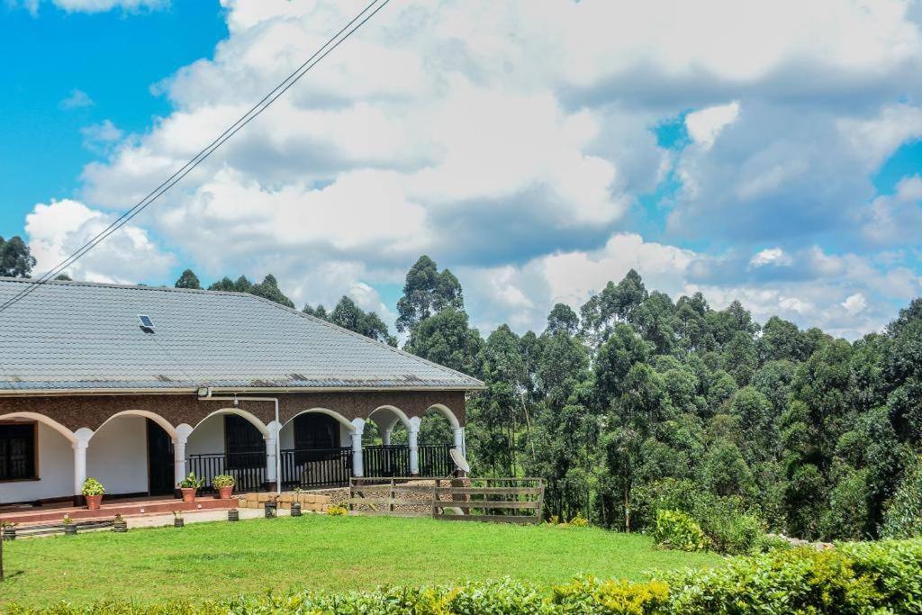 una casa en un campo con árboles en el fondo en The Fortuna Apartment en Kabale