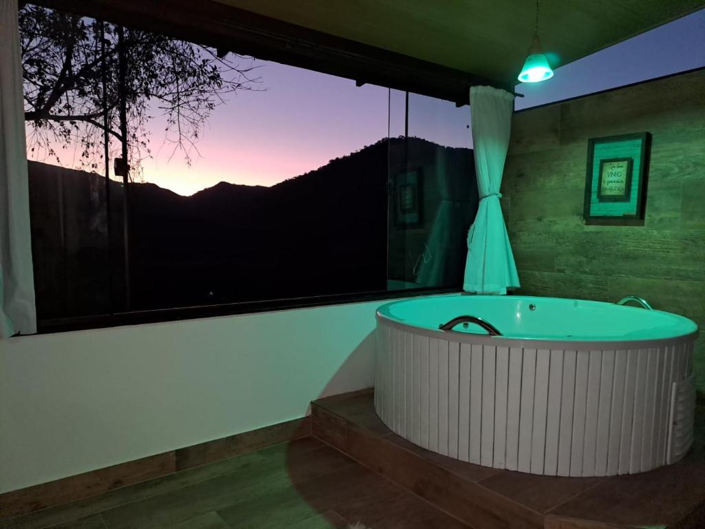 a bath tub in a room with a large window at Pousada e Spa Vrindávana in Teresópolis