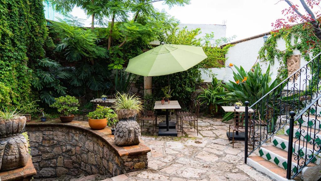 un patio con sombrilla, mesas y plantas en Hotel Casa del Fraile, en Morelia