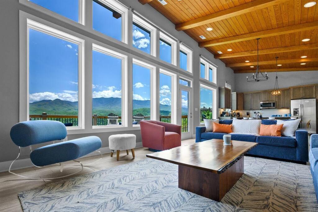een woonkamer met blauwe meubels en grote ramen bij Modern Cabin near Smoky Mountain National Park in Gatlinburg