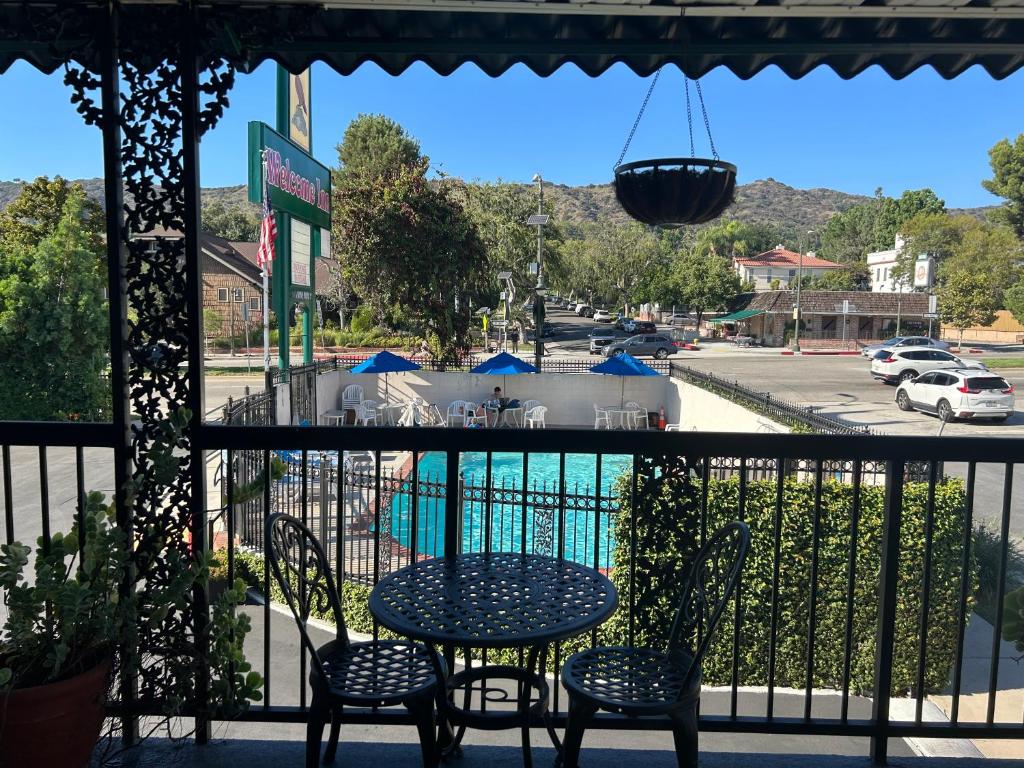a table and chairs on a balcony with a view of a pool at Welcome Inn in Los Angeles