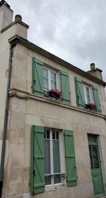 - un bâtiment avec des fenêtres à volets verts et des fleurs dans l'établissement L'esprit de famille, à Semur-en-Auxois