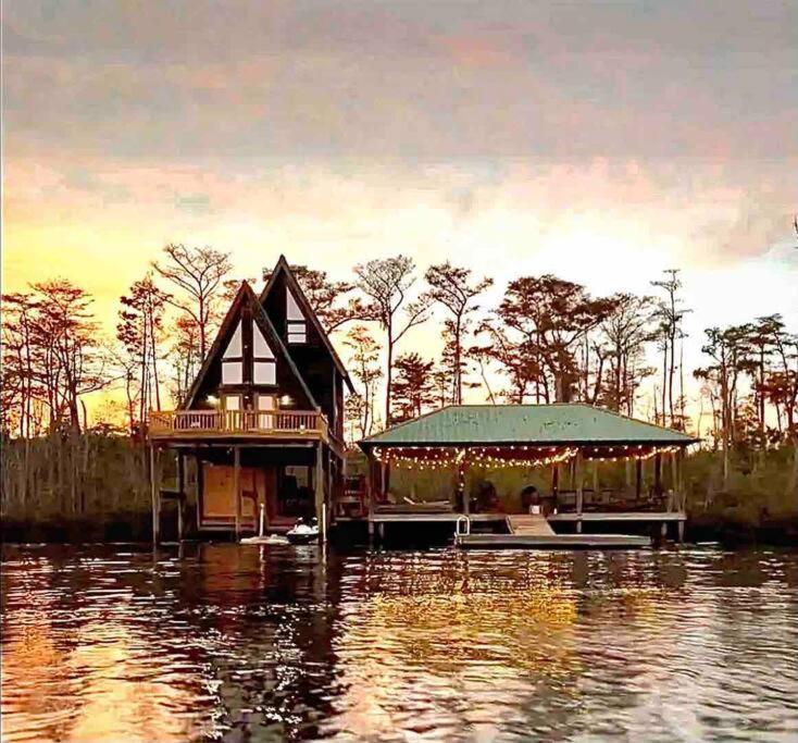 a house on a dock in the middle of the water at Secluded cabin on the water with jet skis, kayaks, & hot tub! Pet friendly in Satsuma
