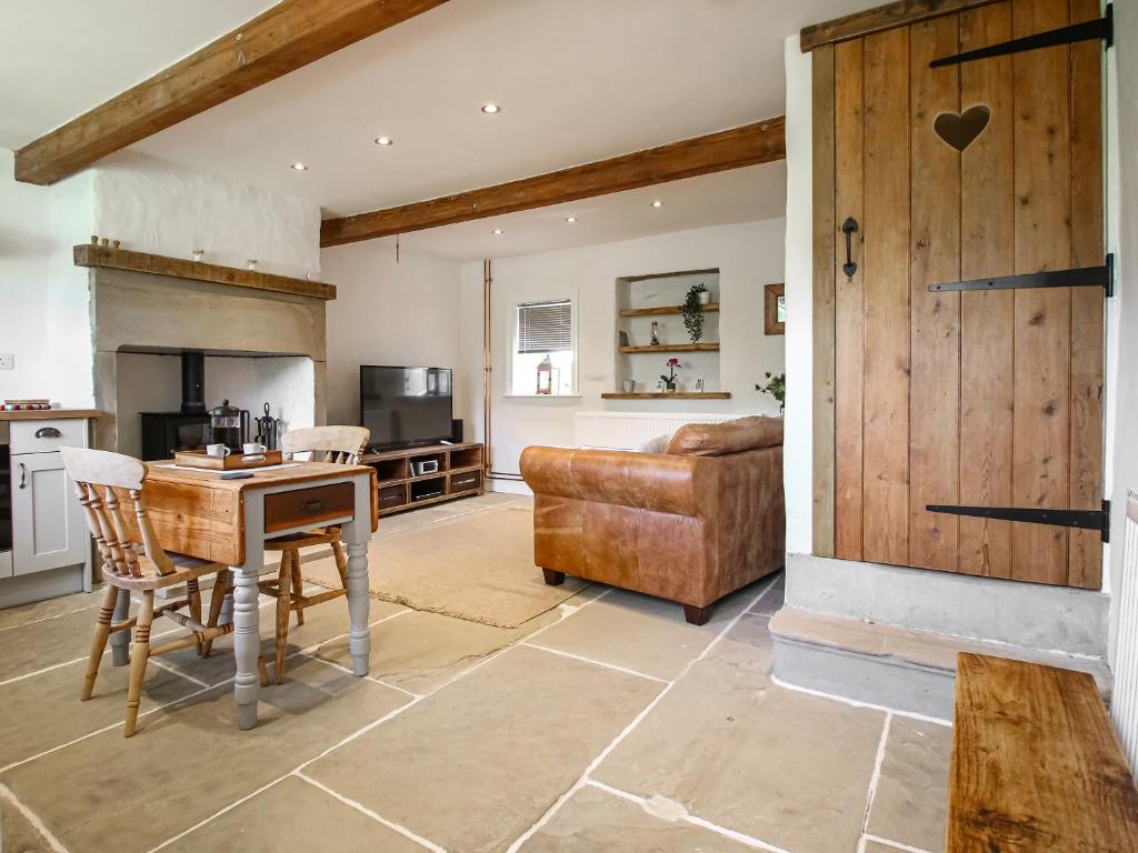 Little Badger Cottage في Kirkburton: مطبخ وغرفة معيشة مع طاولة وأريكة