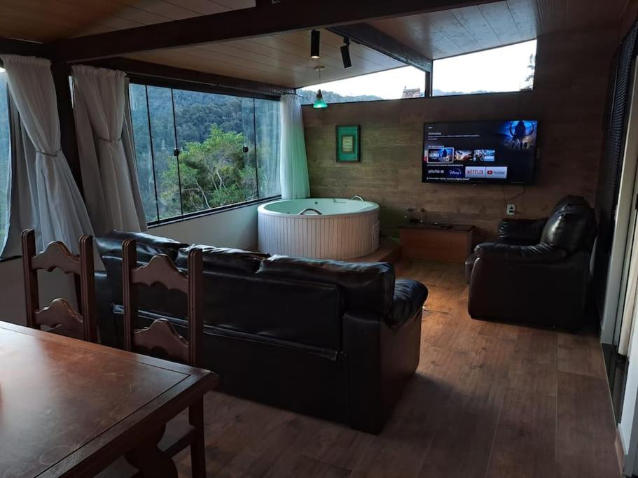 sala de estar con muebles de cuero y TV en Apartamento Panorãmico Master, en Teresópolis