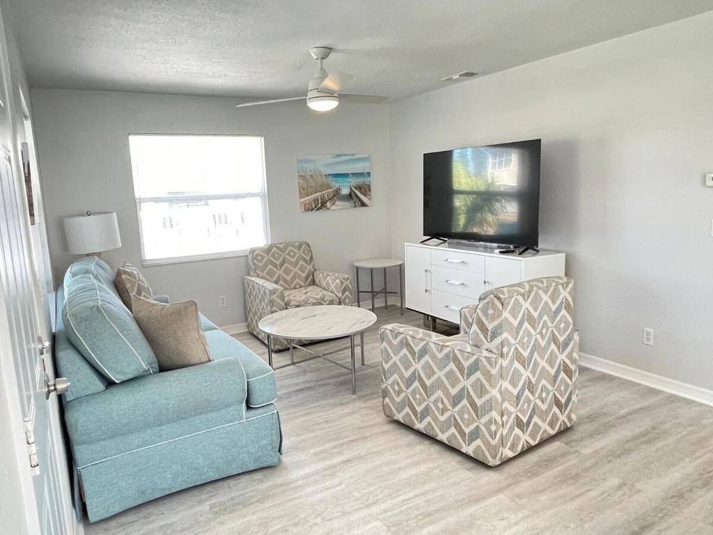 sala de estar con sofá, silla y TV en Beachside Getaway West, en Clearwater Beach