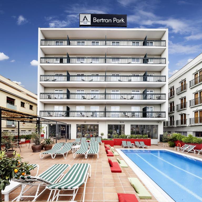 a hotel with a swimming pool and chairs and a building at AQUA Hotel Bertran Park in Lloret de Mar