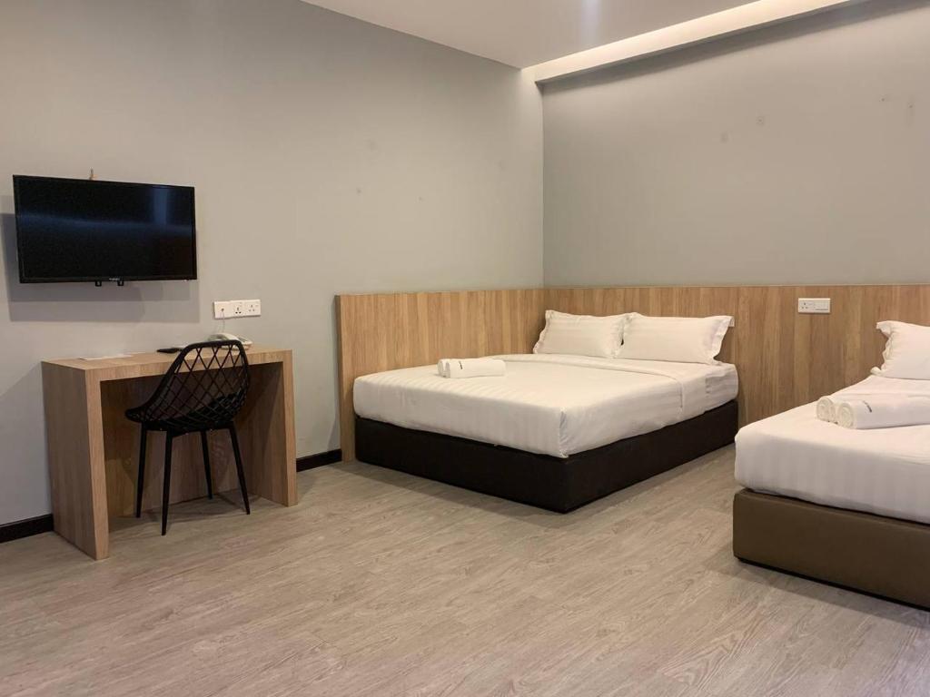 a room with two beds and a flat screen tv at The Daily Hotel in Kota Kinabalu