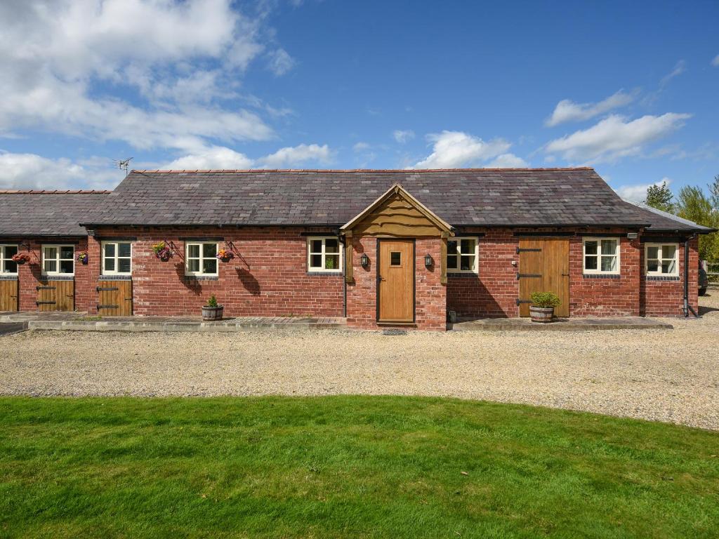 a red brick house with a green lawn in front of it at Orchard View in Minsterley