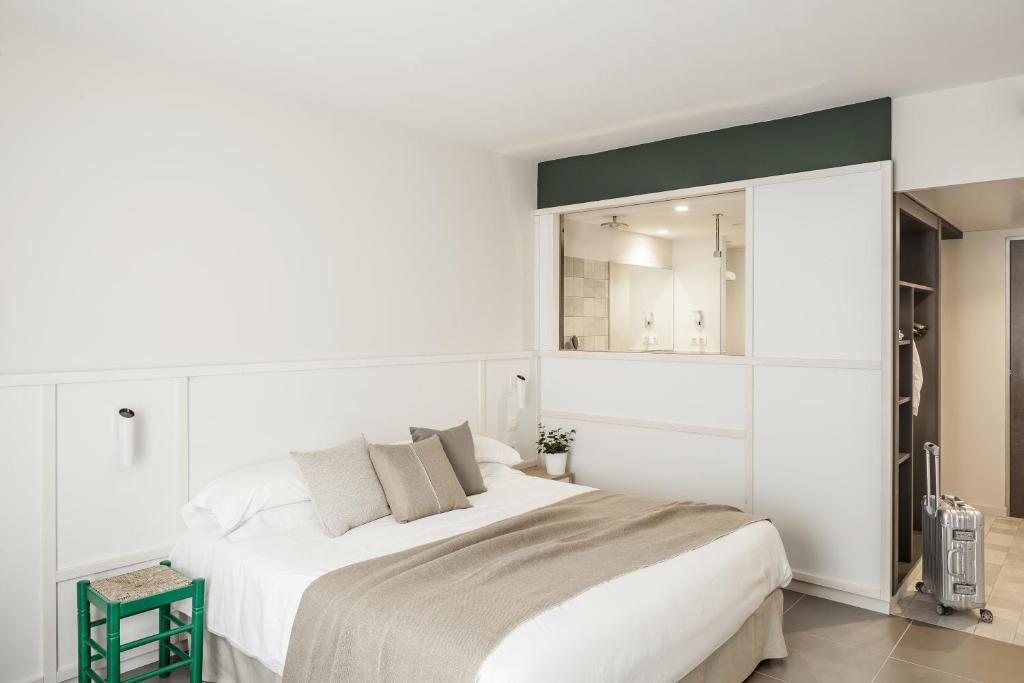 a white bedroom with a large bed and a mirror at AQUA Hotel Bertran Park in Lloret de Mar