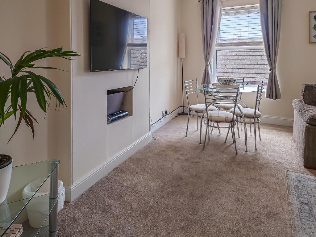 a living room with a table and chairs and a television at Oakleigh By The Sea in Cromer