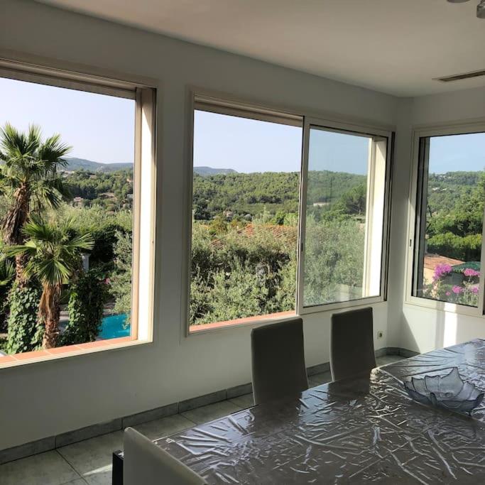 une salle à manger avec une table et quatre fenêtres dans l'établissement Magnifique haut de villa au calme absolu a 10 minutes des plages, à La Bouilladisse