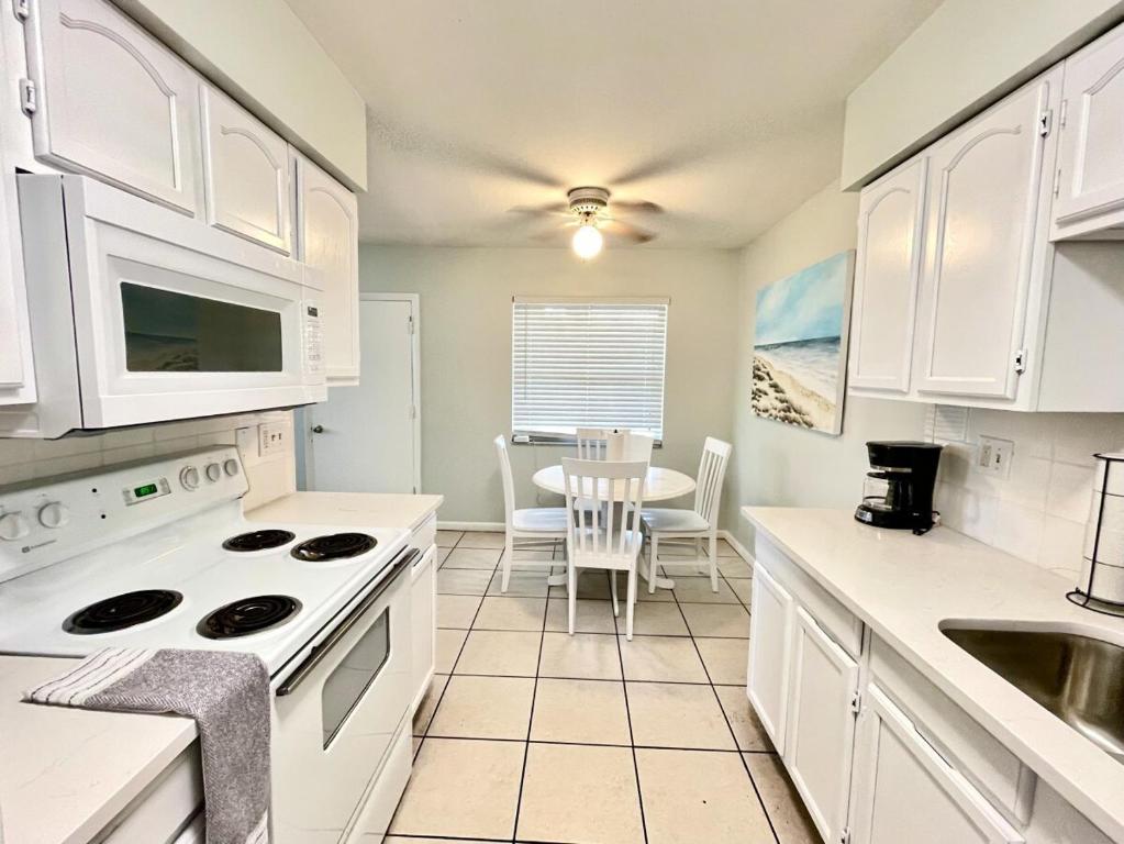 a kitchen with white cabinets and a white stove top oven at Sun, Sand, Coastal Haven 2 in Clearwater Beach