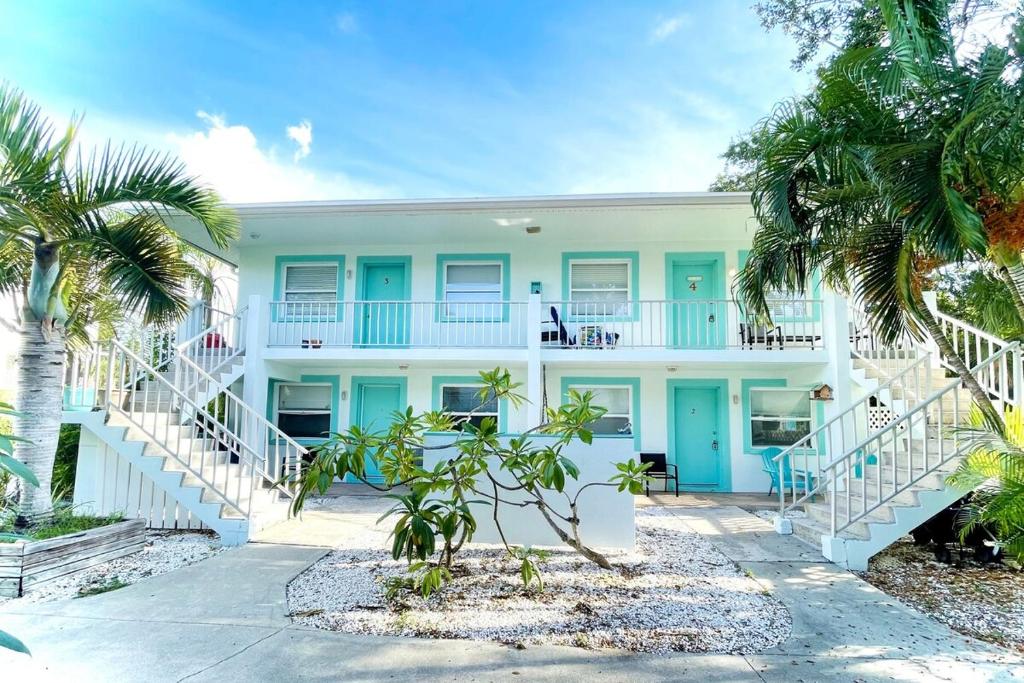 - un bâtiment blanc avec des portes bleues et des palmiers dans l'établissement Sun, Sand, Coastal Haven 1, à Clearwater Beach