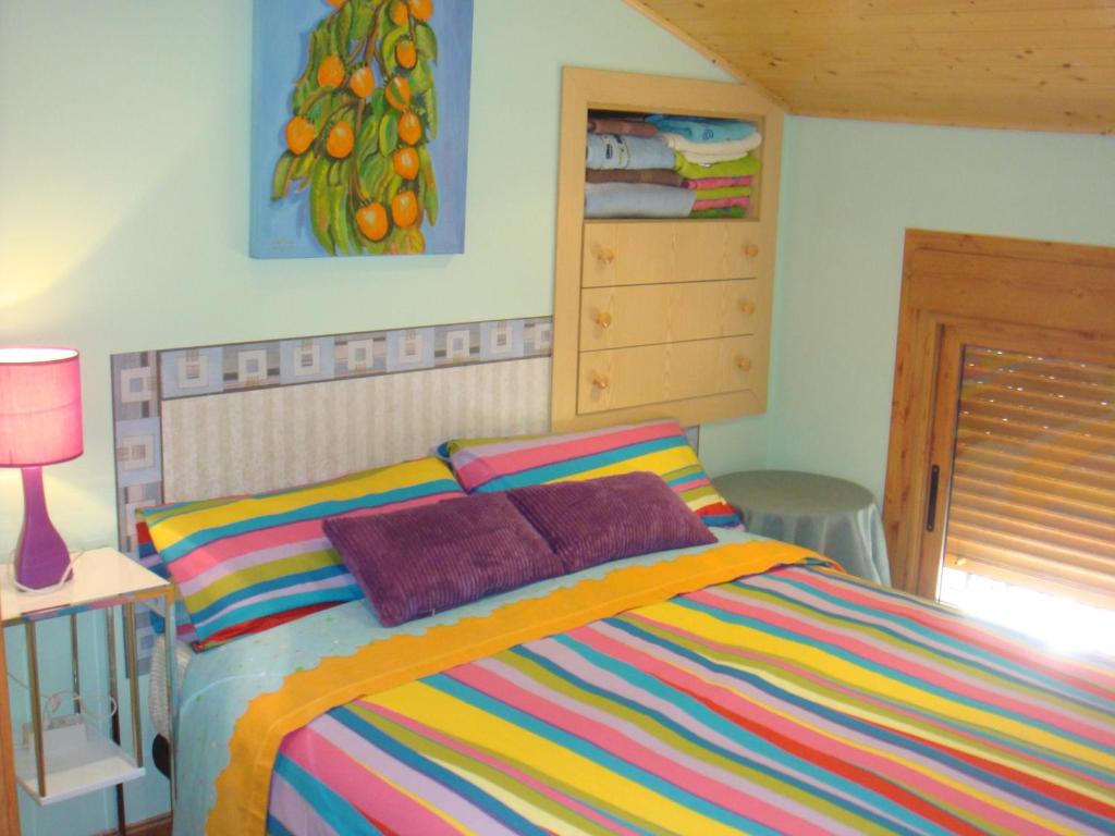 un dormitorio con una cama colorida y una pintura en la pared en La Serreta, en Paüls