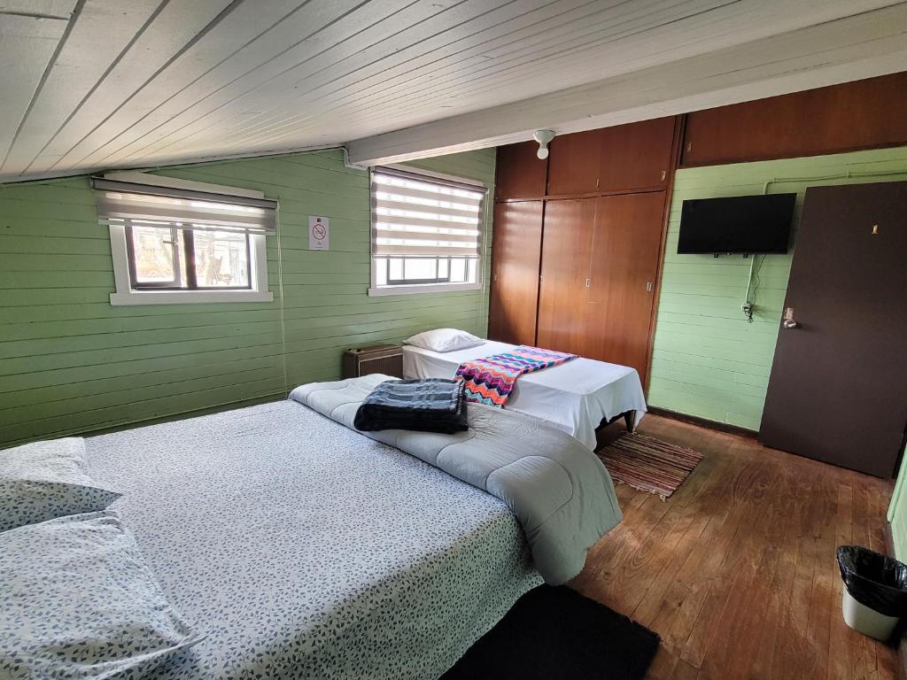 Cette chambre verte comprend 2 lits et une télévision. dans l'établissement HOSTAL PARADISE BLUE OSORNO, à Osorno