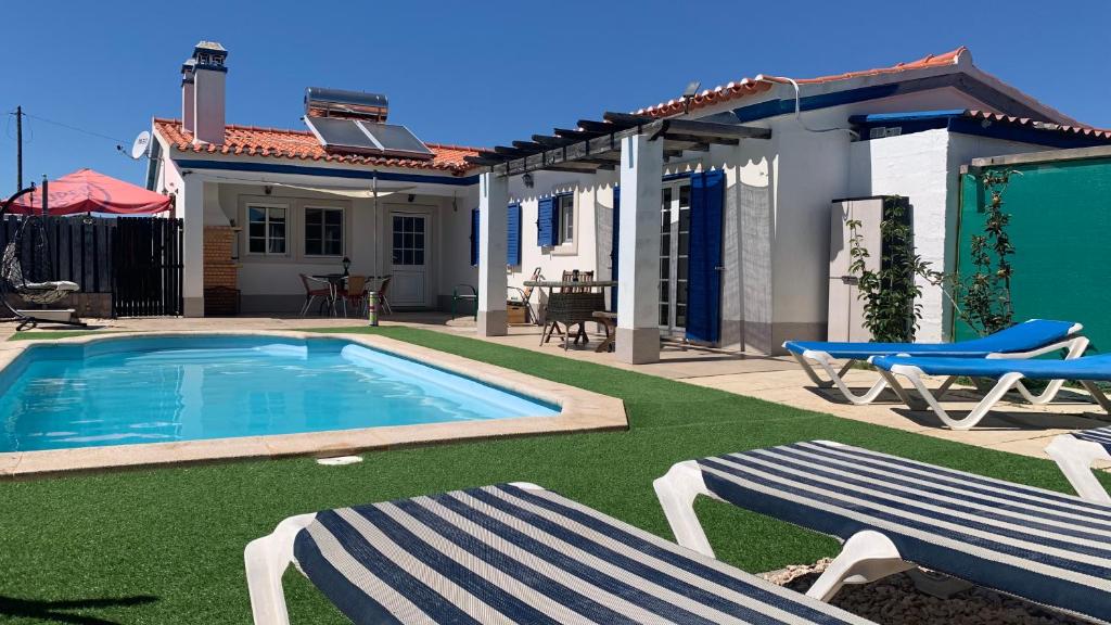 uma piscina com duas cadeiras e uma casa em Windy's Guest House em Aljezur