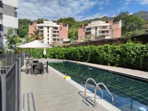 uma piscina com uma mesa e um guarda-sol e alguns edifícios em Hermoso Apartamento en exclusiva zona ibague Calambeo em Ibagué
