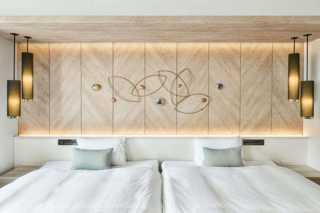 two beds in a room with wooden cabinets at Vessel Hotel Campana Nagoya in Nagoya